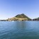 A mountain peak with sailboats in the harbor and a tree lined shoreline